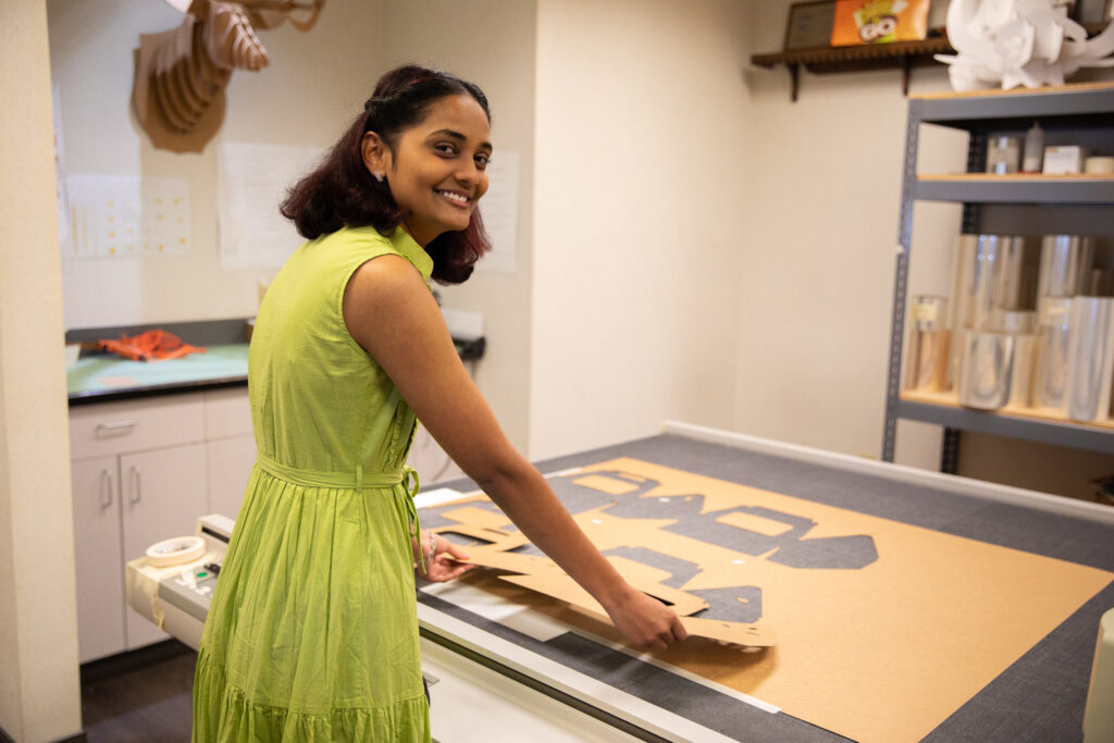 Team member working on die-cut cardboard packaging prototypes at a worktable