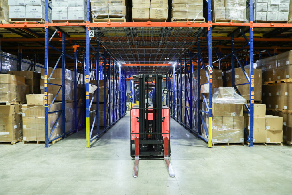 Wide-angle view of an SCT warehouse aisle with tall shelving stocked with packaged inventory